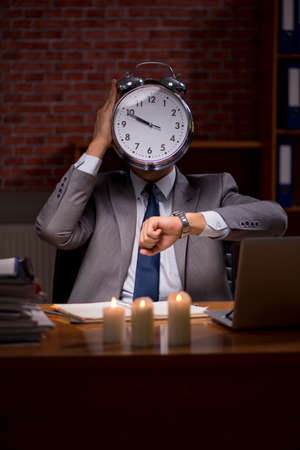 Businessman working late in office with candle lightの写真素材