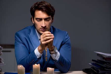 Businessman working late in office with candle lightの写真素材