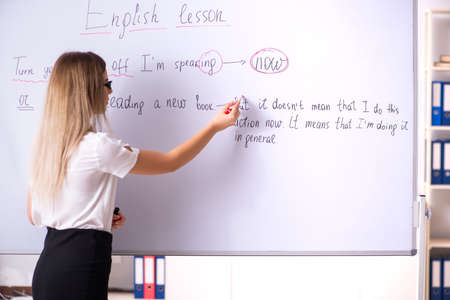 Young female english language teacher standing in front of the b