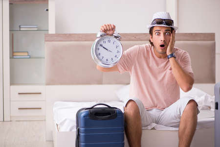 Man with suitcase in bedroom waiting for tripの写真素材