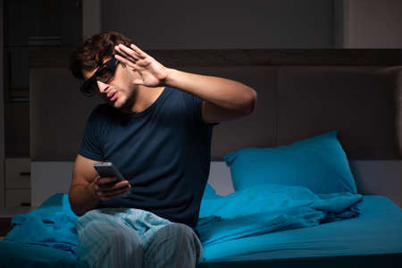 Man watching tv at night in bedの写真素材