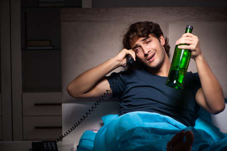 Man drinking in the bed under stressの写真素材