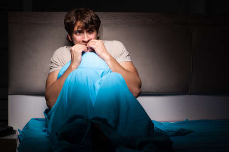 Young man scared in his bed having nightmares