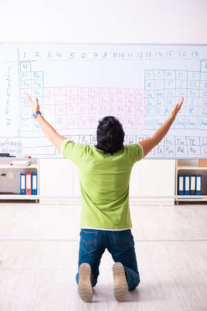 Young male student chemist in front of periodic tableの写真素材