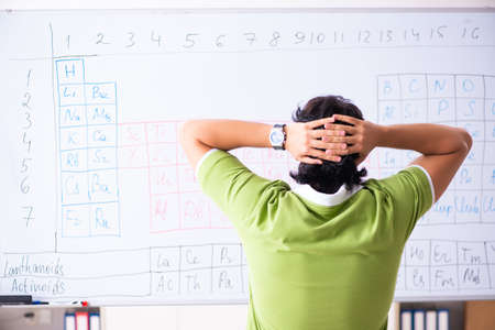 Young male student chemist in front of periodic tableの写真素材