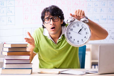 Young male student chemist in front of periodic tableの写真素材