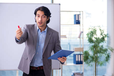 Young handsome teacher in front of whiteboardの写真素材
