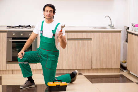 Young contractor repairing oven in kitchenの写真素材