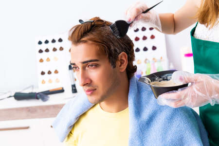 Woman hairdresser applying dye to man hairの写真素材