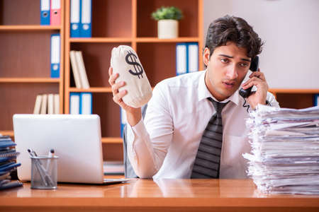 Young handsome businessman unhappy with excessive workの写真素材