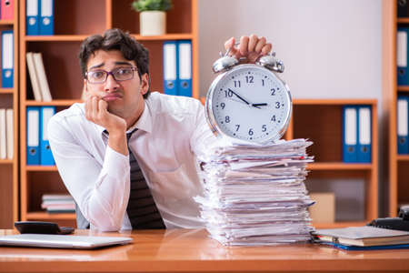 Young handsome businessman unhappy with excessive workの写真素材