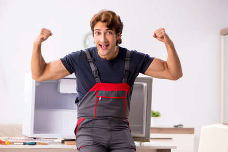Young handsome contractor repairing fridgeの写真素材
