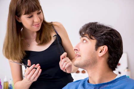 Young attracrive man visiting female barberの写真素材