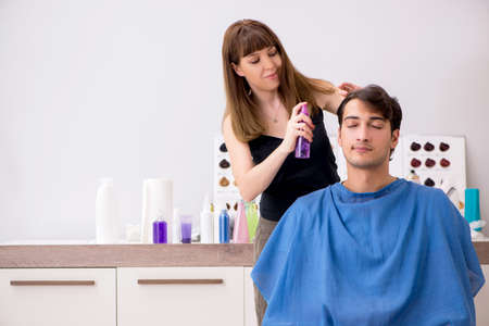 Young attracrive man visiting female barberの写真素材