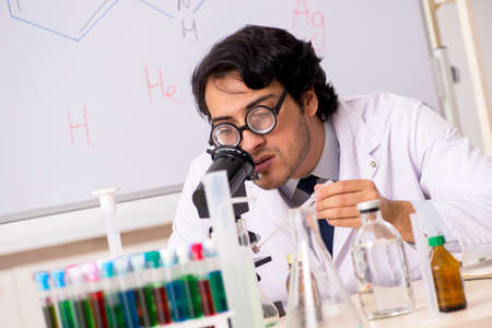 Young funny chemist in front of white board