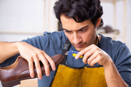 Young man repairing shoes in workshop