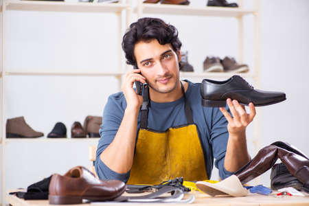 Young man repairing shoes in workshopの写真素材