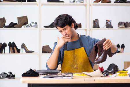 Young man repairing shoes in workshop