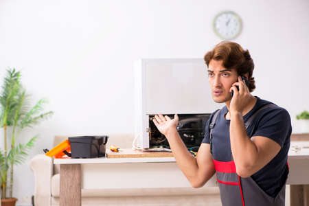 Young handsome contractor repairing fridgeの写真素材