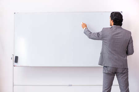 Young handsome businessman standing in front of whiteboardの写真素材