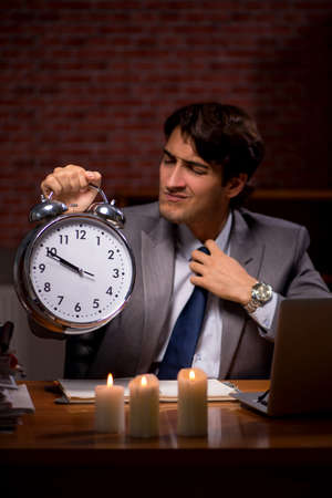 Businessman working late in office with candle lightの写真素材