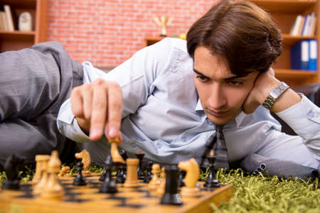 Young handsome boss playing chess during break