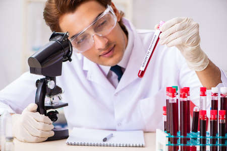 Young handsome lab assistant testing blood samples in hospitalの写真素材
