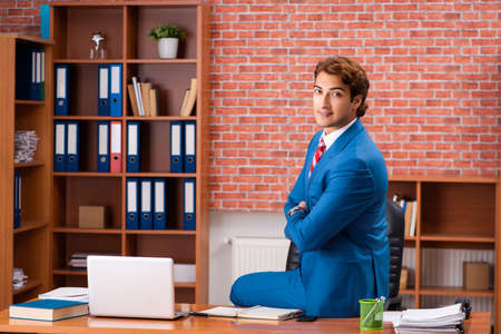 Young handsome employee sitting in the officeの写真素材