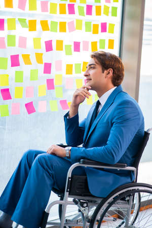 Young handsome man in wheelchair with many conflicting prioritieの写真素材