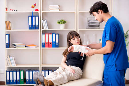 Young woman with bandaged arm visiting male doctor traumotologisの写真素材