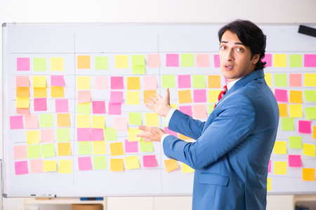 Young handsome employee with many conflicting priorities