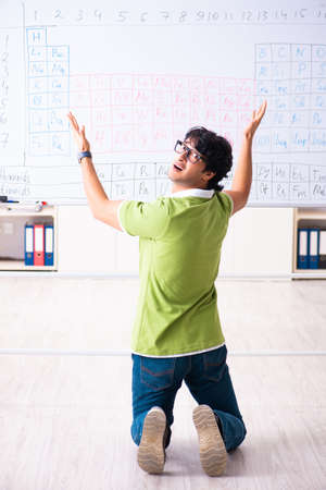 Young male student chemist in front of periodic tableの写真素材