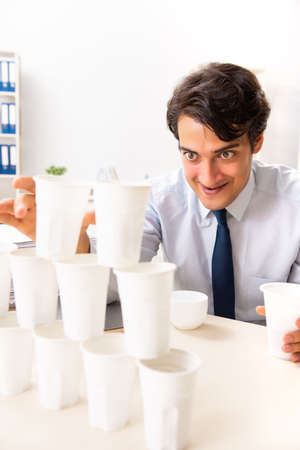 Young employee building pyramid from plastic cupsの写真素材