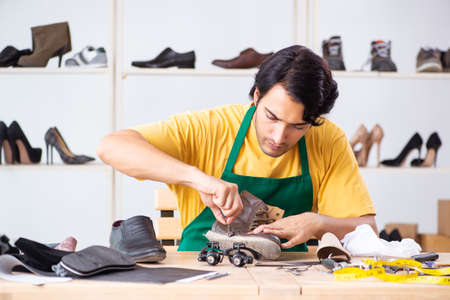 Young man repairing shoes in workshopの写真素材