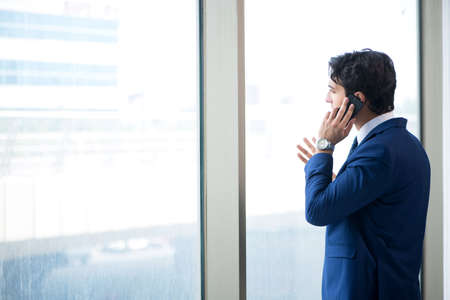 Young handsome businessman standing at the windowの写真素材