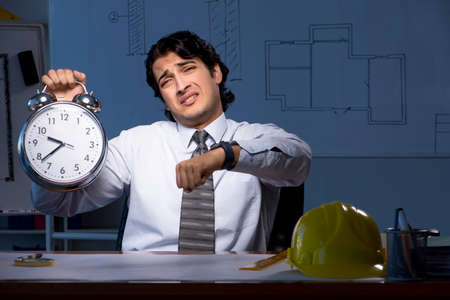 Young construction architect working on project at nightの写真素材