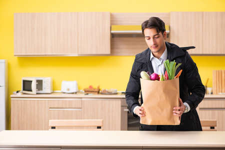 Young handsome man with vegetables in kitchenの写真素材