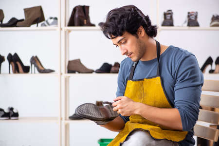 Young man repairing shoes in workshopの写真素材