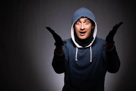Young gangster in hood on grey backgroundの写真素材
