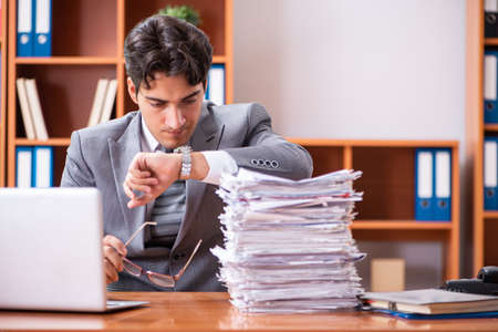 Young handsome businessman unhappy with excessive workの写真素材