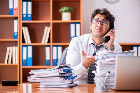 Young handsome businessman unhappy with excessive workの写真素材