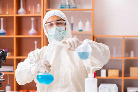 Young biochemist wearing protective suit working in the lab