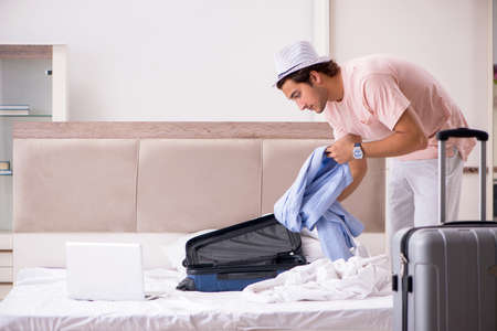 Man with suitcase in bedroom waiting for tripの写真素材