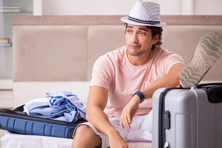 Man with suitcase in bedroom waiting for tripの写真素材