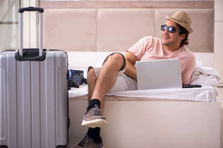 Man with suitcase in bedroom waiting for tripの写真素材