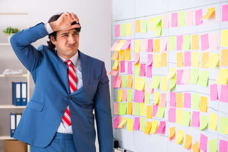 Young handsome employee with many conflicting priorities
