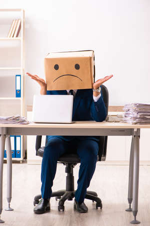 Unhappy man employee with box instead of his headの写真素材