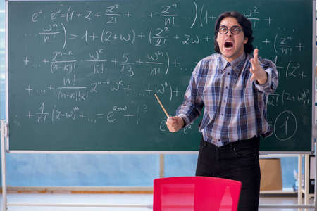 Young funny math teacher in front of chalkboard