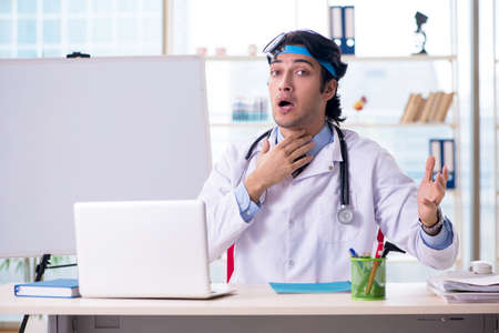 Young handsome doctor otolaryngologist in front of whiteboardの写真素材