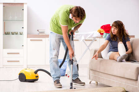 Husband helping leg injured wife in houseworkの写真素材